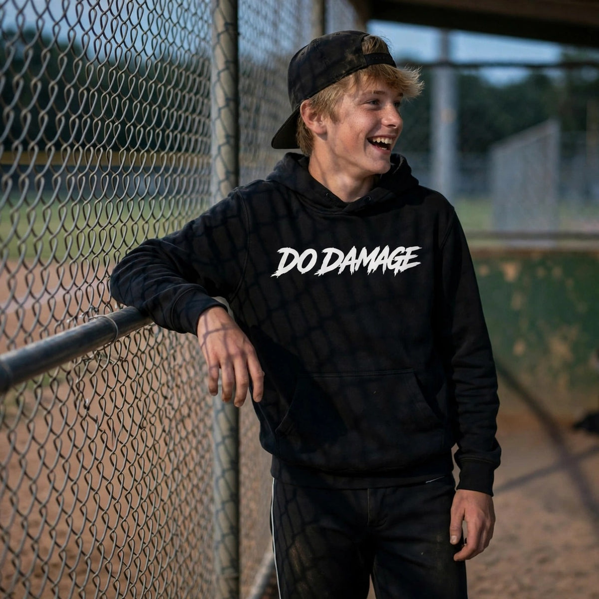 HTB Do Damage OG Hoodie - player on the dugout fence at dusk