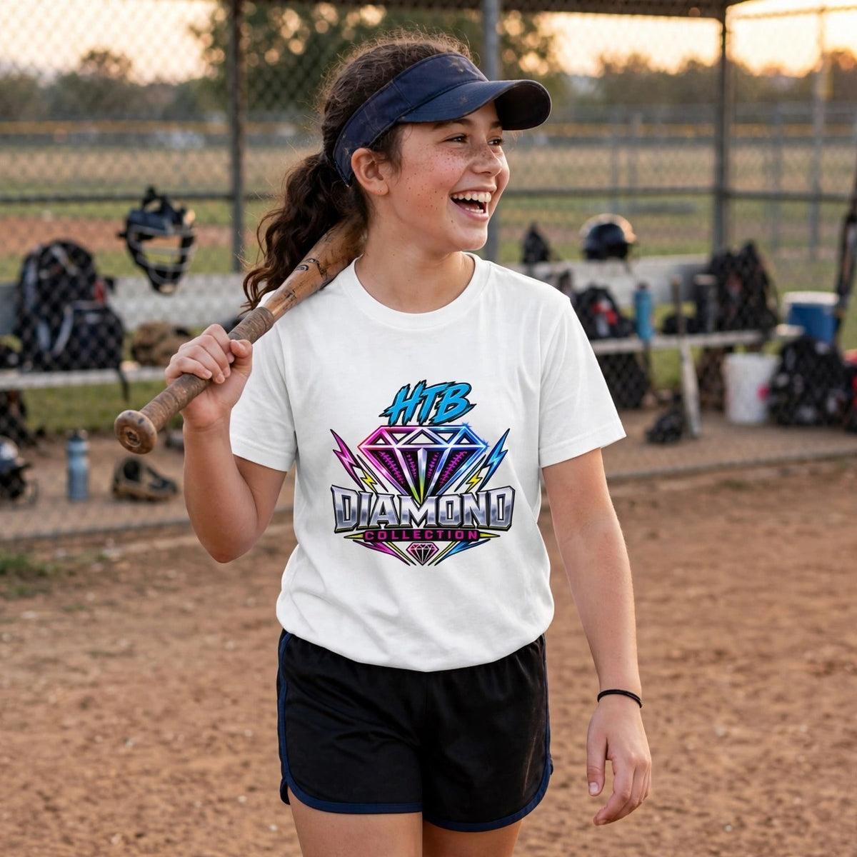 HTB Diamond Collection Youth Tee in White — girl softball player with a bat walking off the field